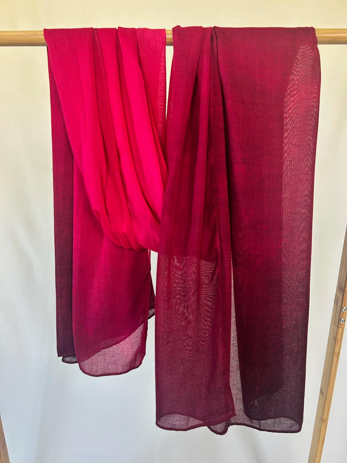 Vibrant magenta and deep burgundy lightweight scarves drape elegantly over a wooden garment rack.