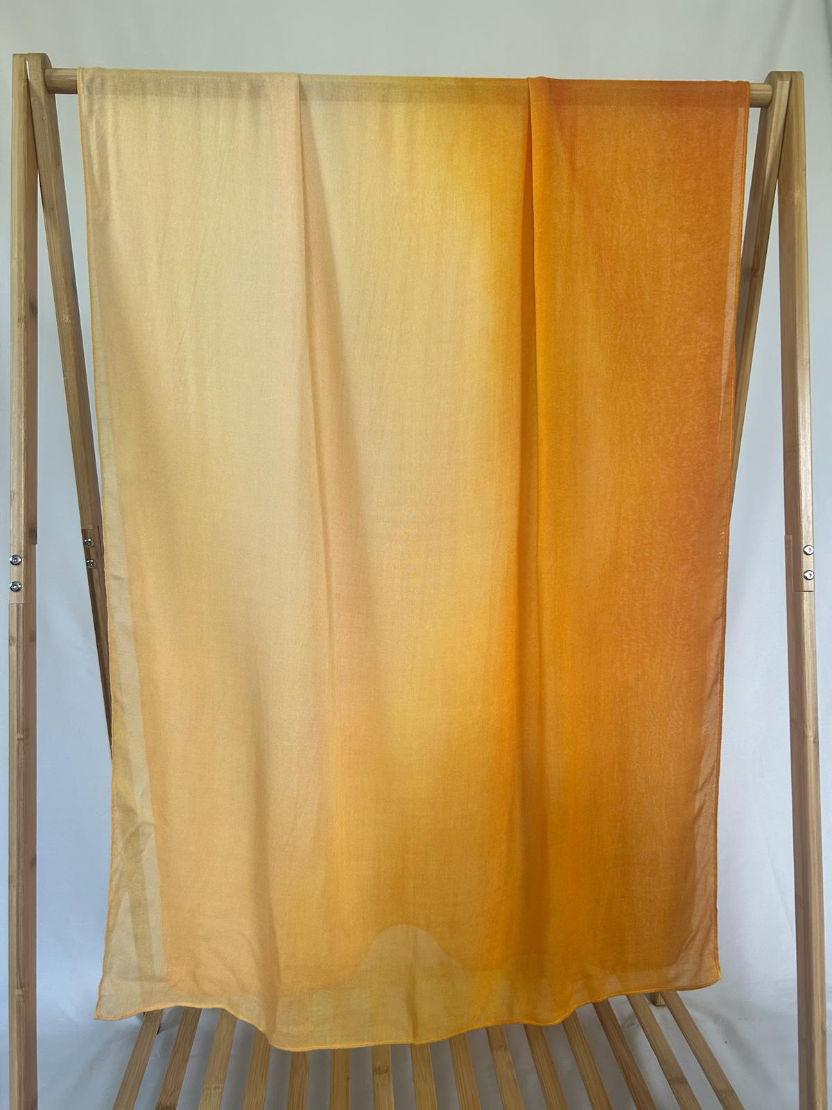A lightweight yellow and orange ombre scarf drapes elegantly over a wooden display rack.